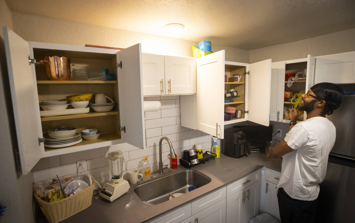 Angelo Crews shows off cupboards full of dishes, cups and more, all of which were donated, at t ...