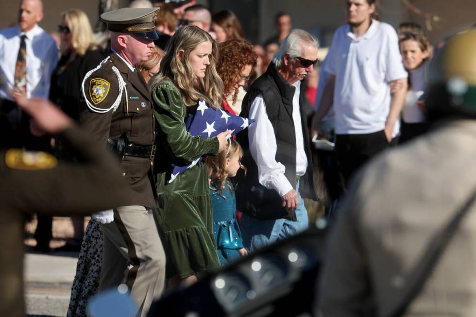 Ashlee Pulsipher, widow of Las Vegas police officer Colton Pulsipher, center, hugs the flag dur ...