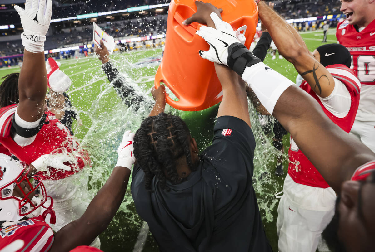 UNLV players and staff dump a bucket of gatorade onto UNLV interim head coach Del Alexander as ...