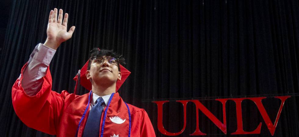 A graduate waves to the crowd after walking the stage during the UNLV winter commencement at th ...