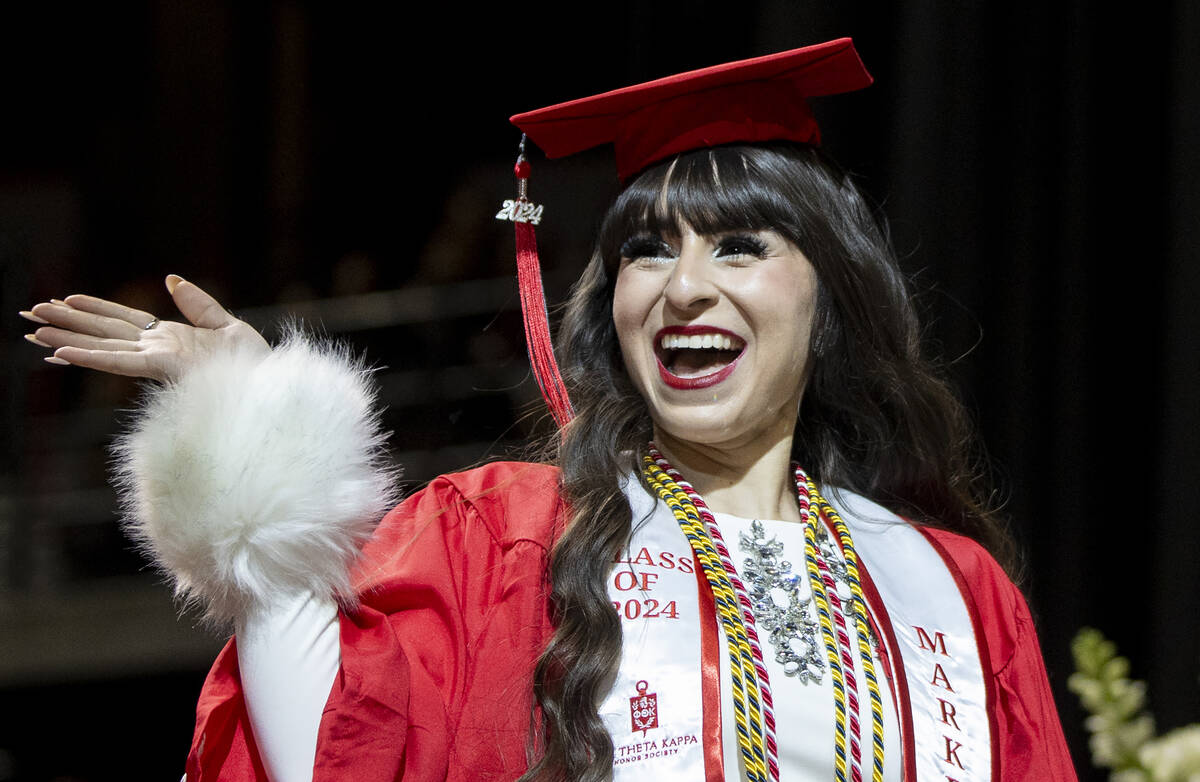 A graduate waves to the crowd while walking the stage during the UNLV winter commencement at th ...