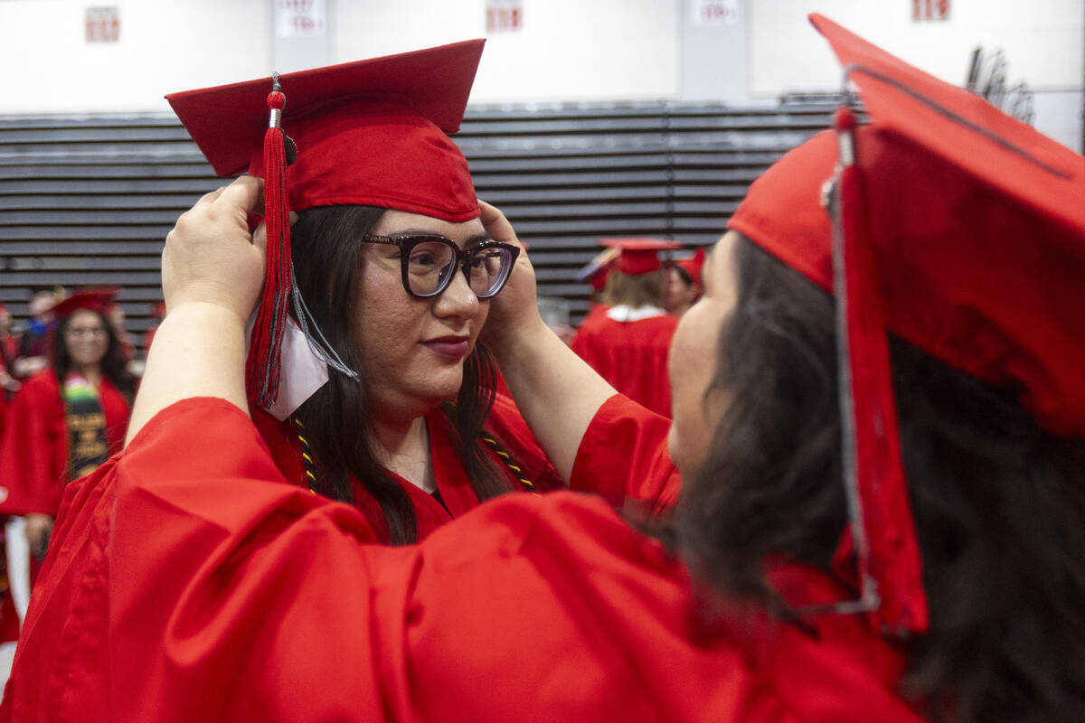 Ambur China, left, receives help from Eliza Brink, right, before the UNLV winter commencement a ...