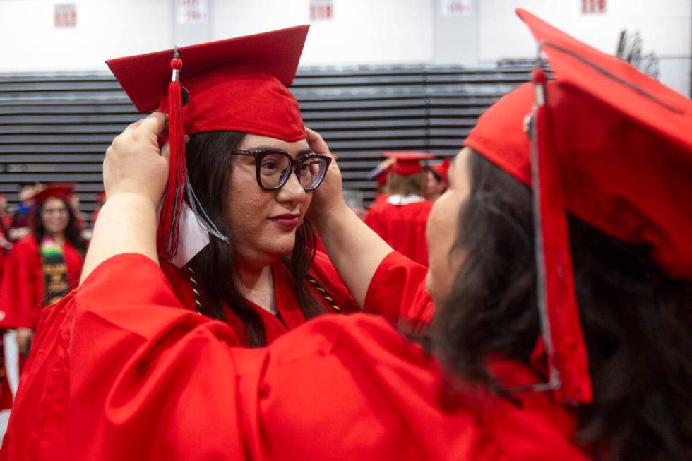 Ambur China, left, receives help from Eliza Brink, right, before the UNLV winter commencement a ...