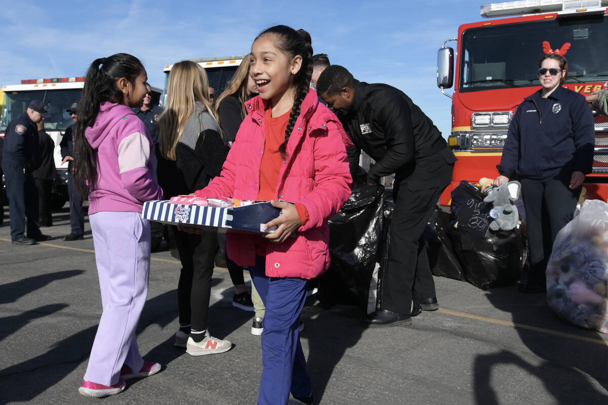 Marley Soriano reacts after getting a present as local firefighters deliver toys to children at ...