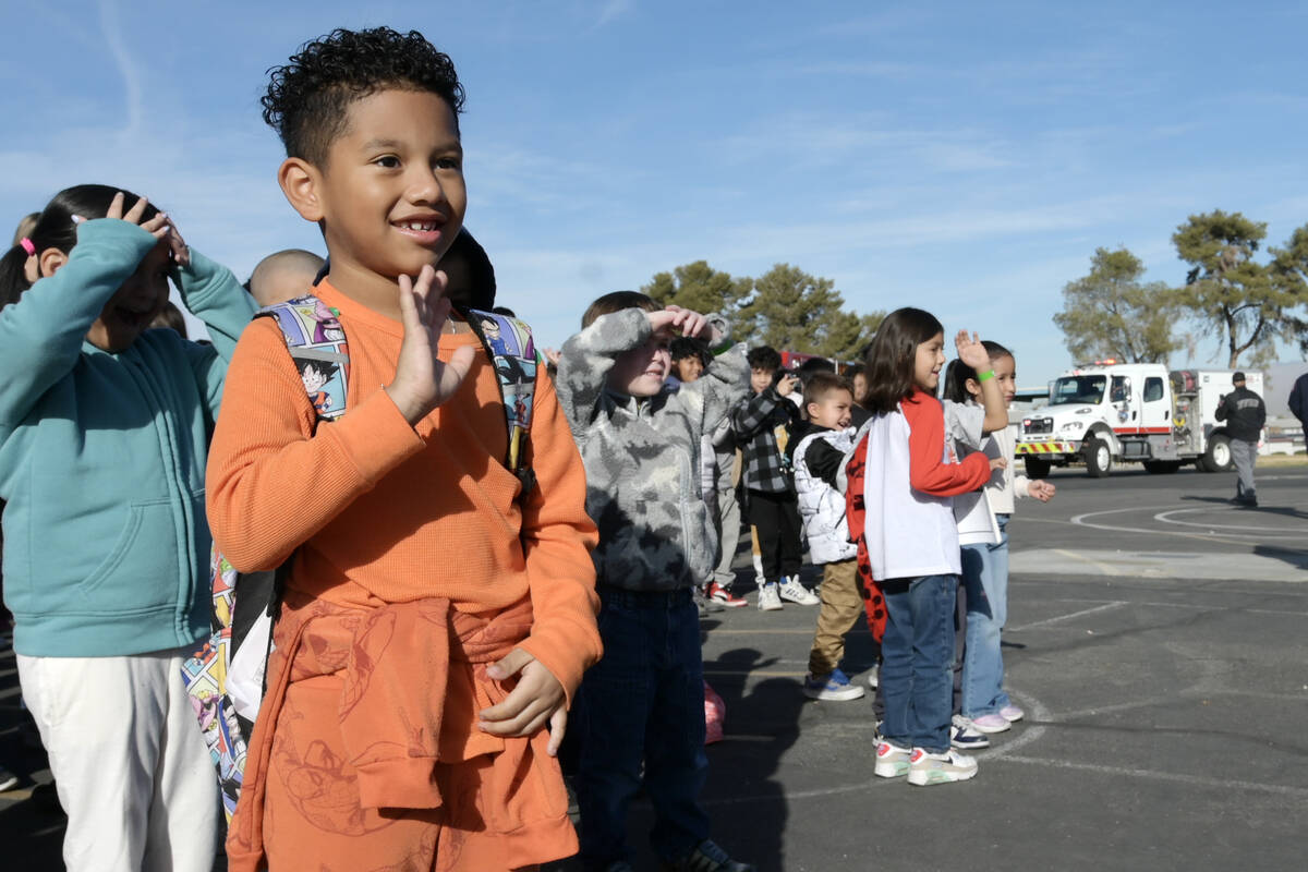 Julian Antnunez waves as firefighters arrive to deliver toys at Will Buckley Elementary School ...