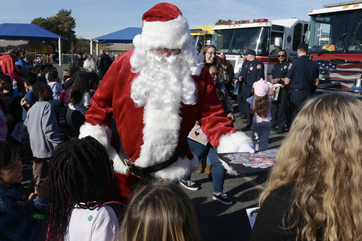 Santa Claus assists local firefighters as they deliver toys to children at Will Buckley Element ...