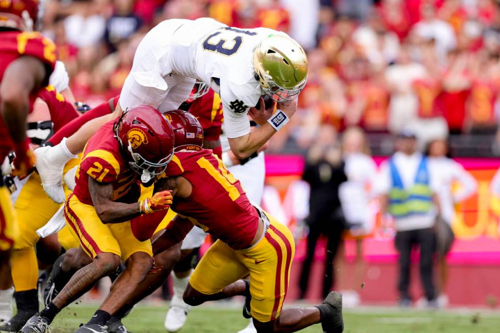 Notre Dame quarterback Riley Leonard, top, dives over Southern California cornerback Greedy Van ...