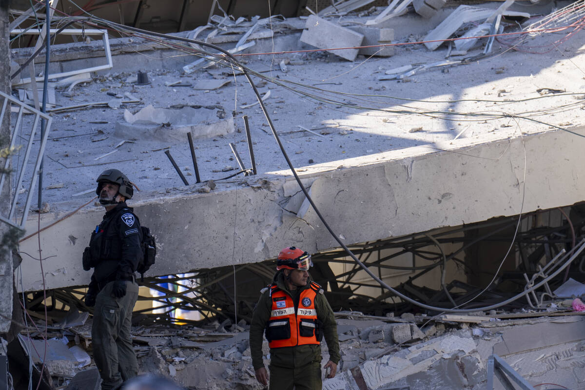 An officer from the home front command military unit and a policeman examine the damage after a ...