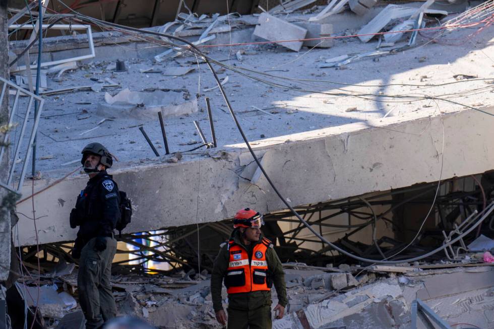 An officer from the home front command military unit and a policeman examine the damage after a ...