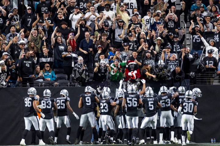 Raiders players celebrate with the ‘Black Hole’ fan area after recovering a fumbl ...