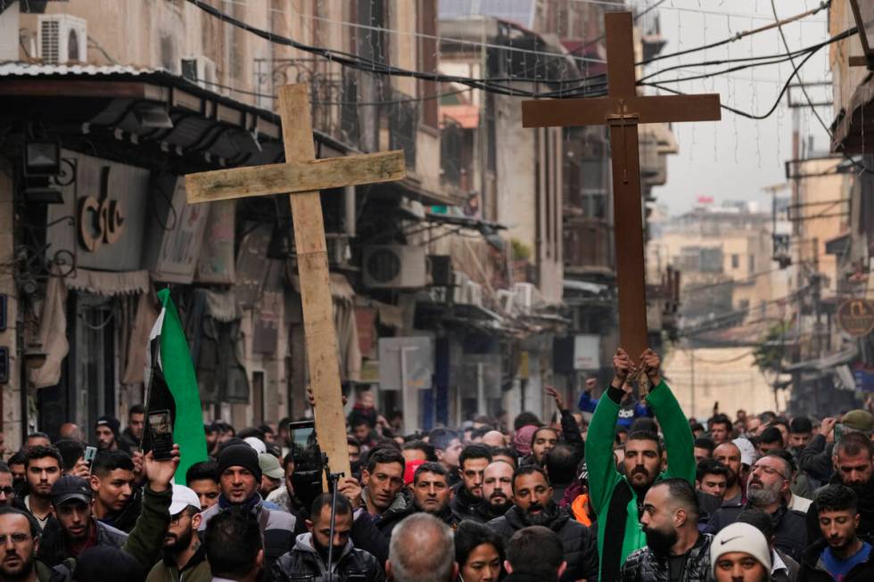 Syrian Christians hold up crosses and shout slogans in Damascus, Syria, Tuesday, Dec. 24, 2024 ...