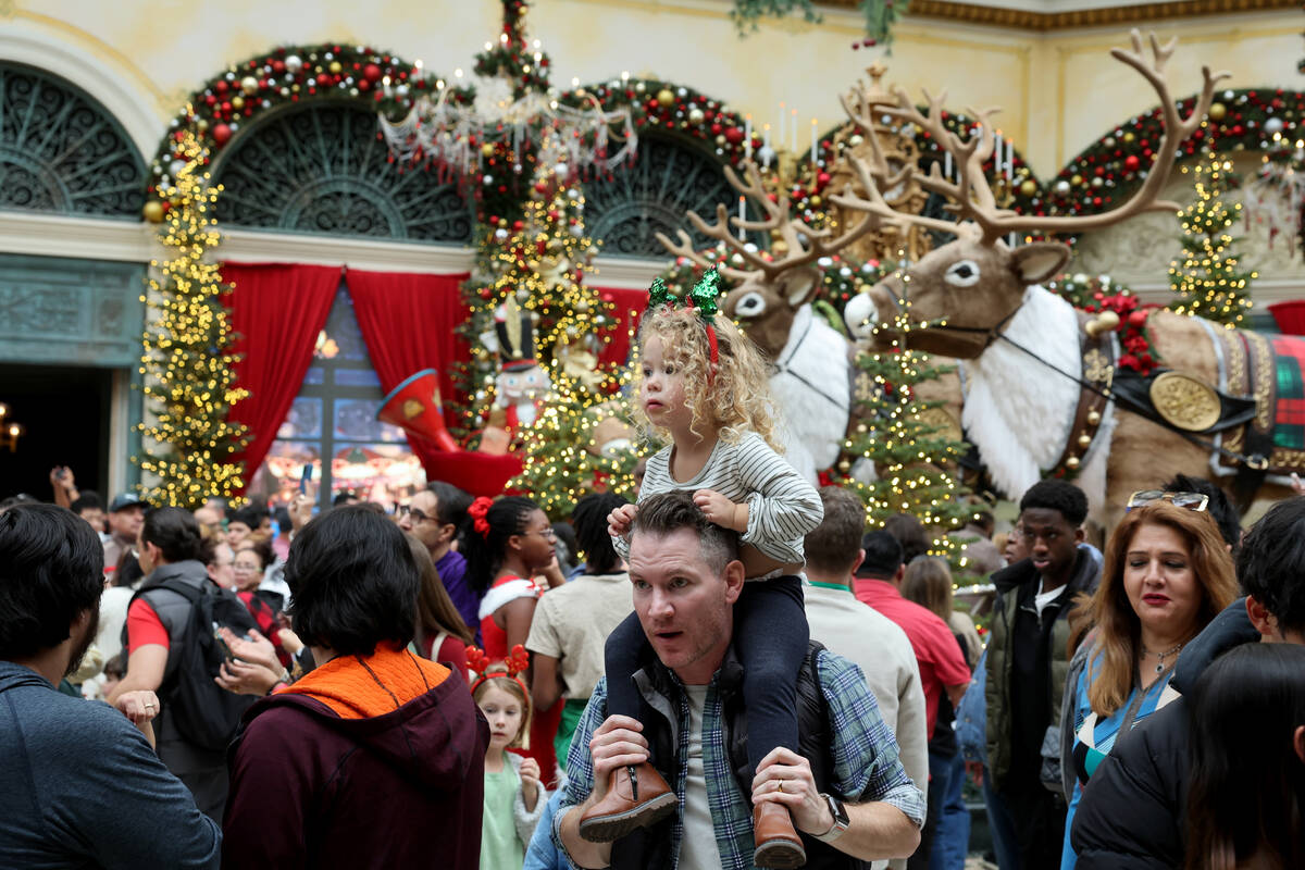 Cleo Nelson, 3, and her dad Frederick of Las Vegas take in ‘Twas holiday flower display ...