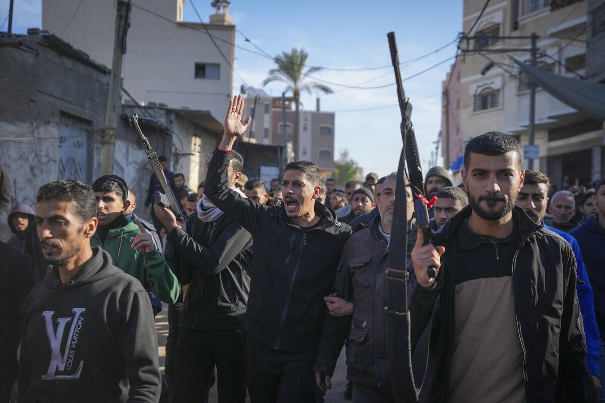 Relatives and neighbors, two of them holding guns, walk during the funeral procession of a vict ...