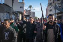 Relatives and neighbors, two of them holding guns, walk during the funeral procession of a vict ...