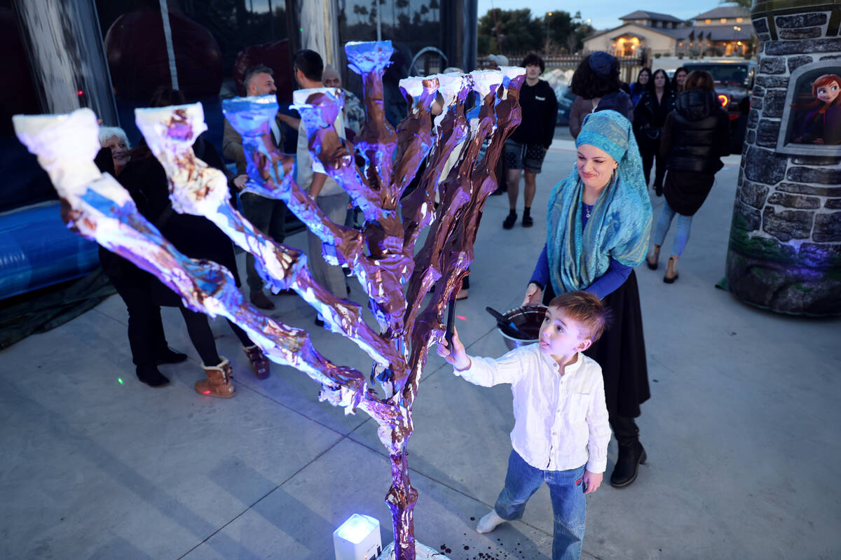 Eli Yosef, 5, and his mother Ester Yosef cover the menorah with chocolate during a lighting cel ...