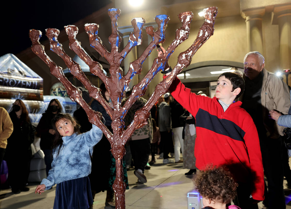 Children cover the menorah with chocolate during a lighting celebration on the first night of H ...