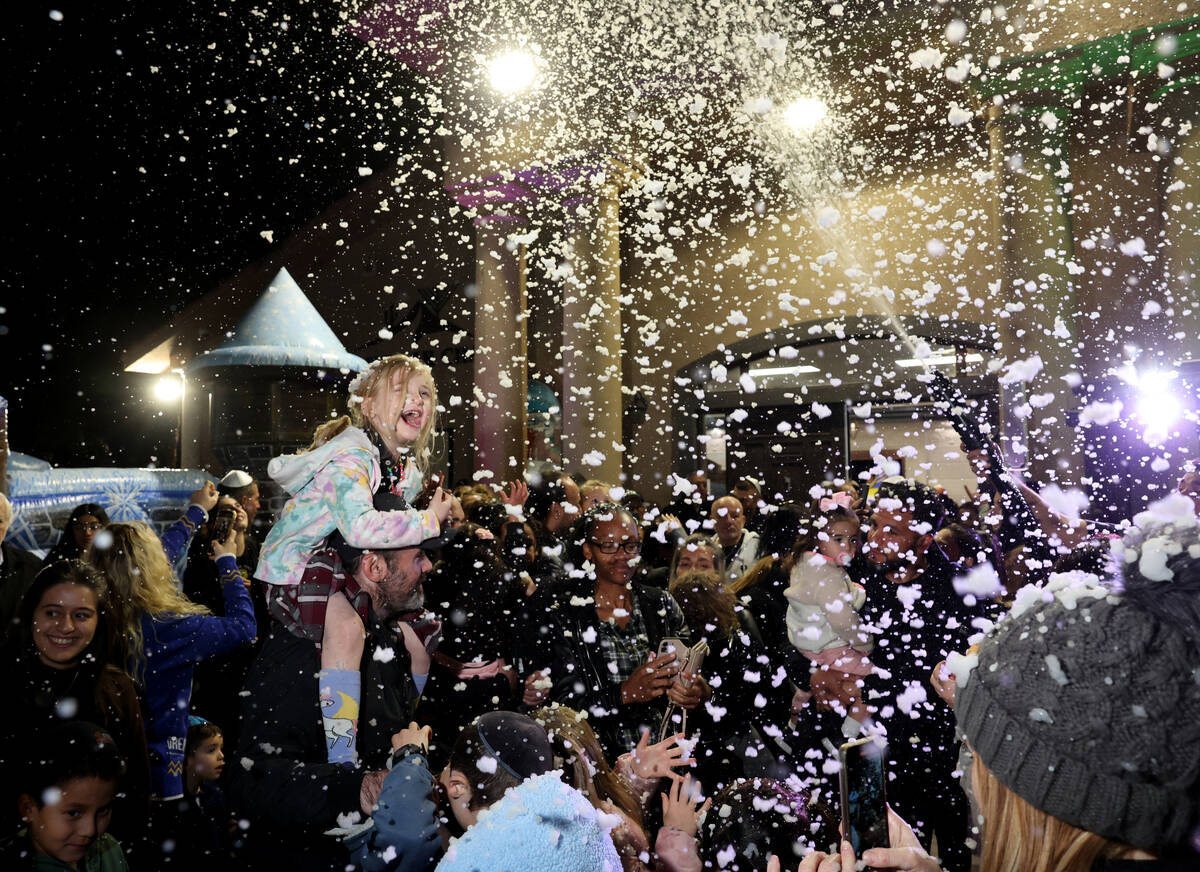 Children dance under a “snowfall” during a menorah lighting celebration on the fi ...