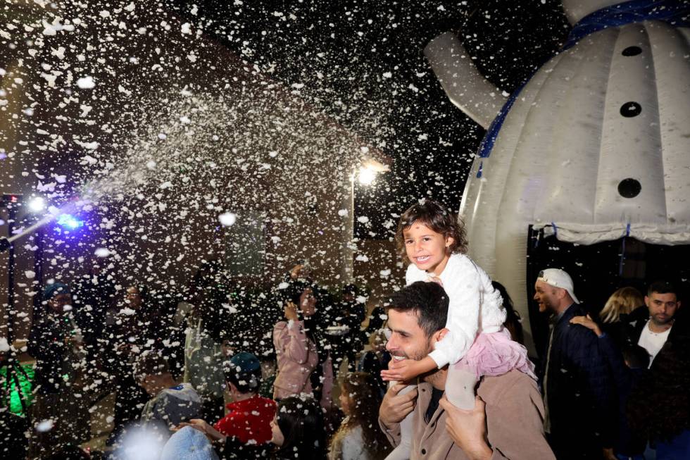 Aliyah Hauser, 4, and her father David dance under a “snowfall” during a menorah lighting c ...