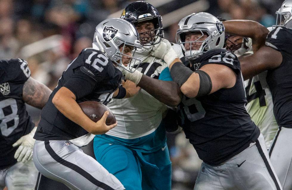 Raiders quarterback Aidan O'Connell (12) escapes pressure as guard Jackson Powers-Johnson (58) ...