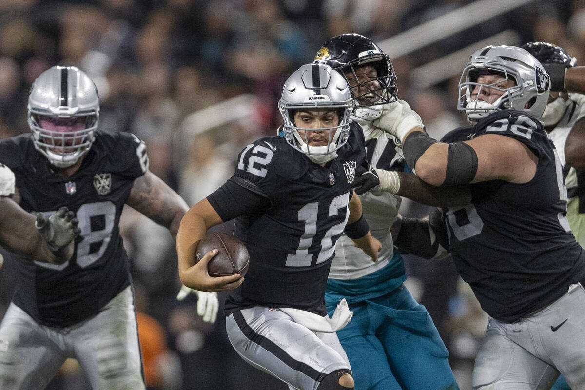 Raiders quarterback Aidan O'Connell (12) escapes pressure as guard Jackson Powers-Johnson (58) ...