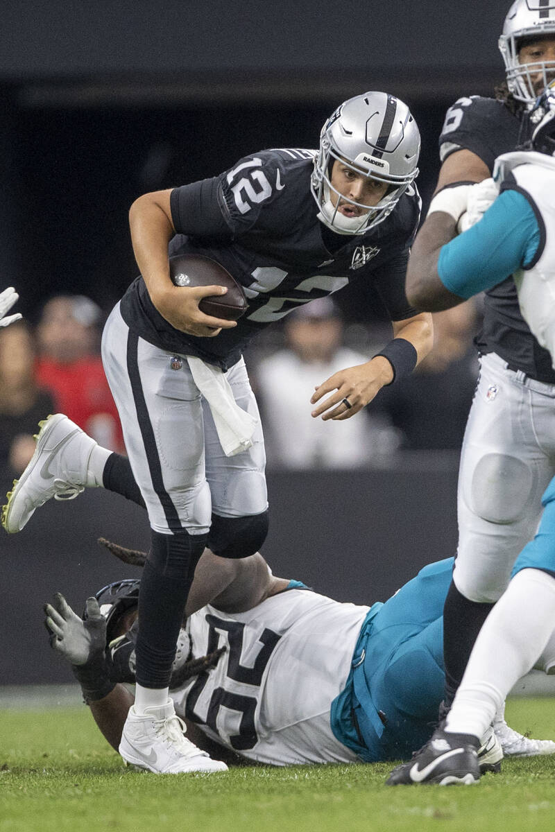 Raiders quarterback Aidan O'Connell (12) avoids a tackle from Jacksonville Jaguars defensive ta ...