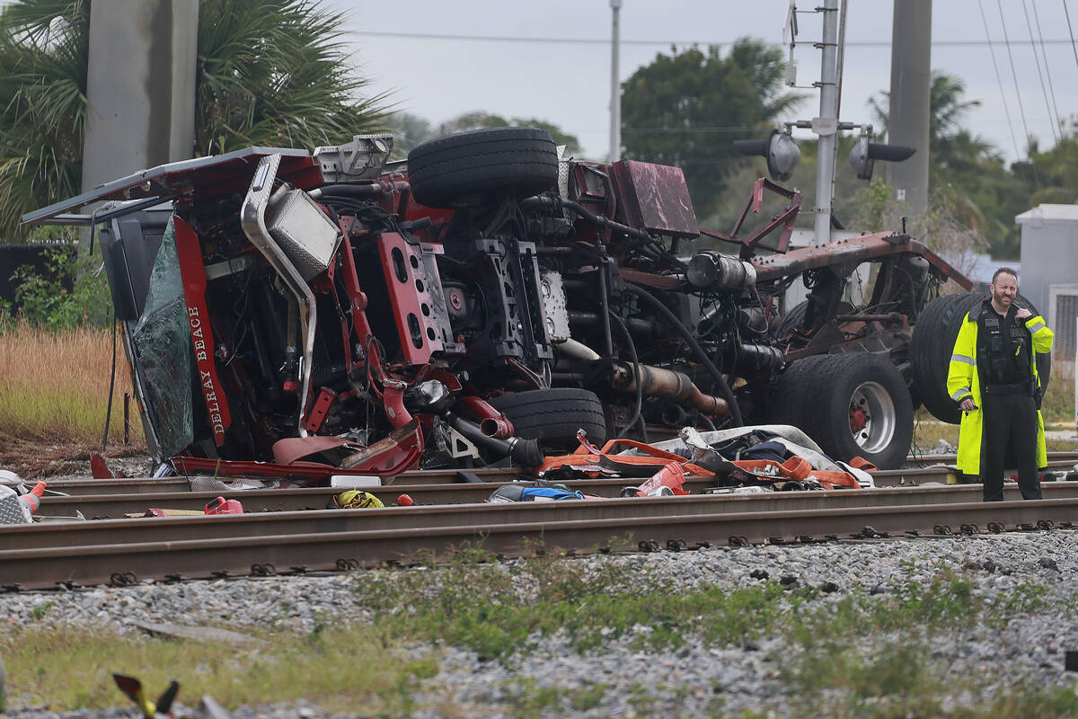 A damaged fire truck is on its side after colliding with a train in downtown Delray Beach, Fla. ...