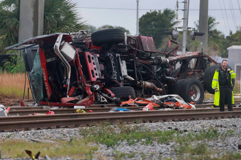 A damaged fire truck is on its side after colliding with a train in downtown Delray Beach, Fla. ...