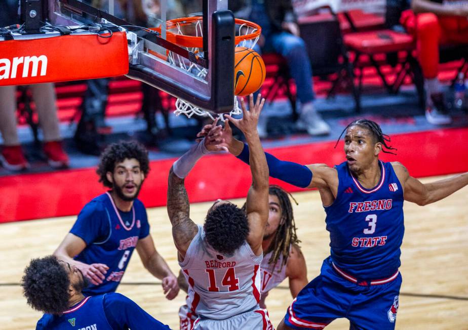 UNLV guard Jailen Bedford (14) puts the ball up over Fresno State Bulldogs forward Elijah Price ...