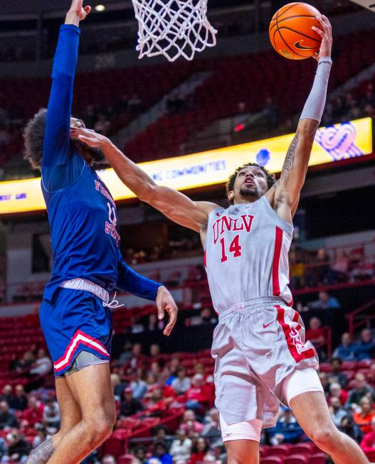 UNLV guard Jailen Bedford (14) battles to shoot against Fresno State Bulldogs forward Mykell Ro ...