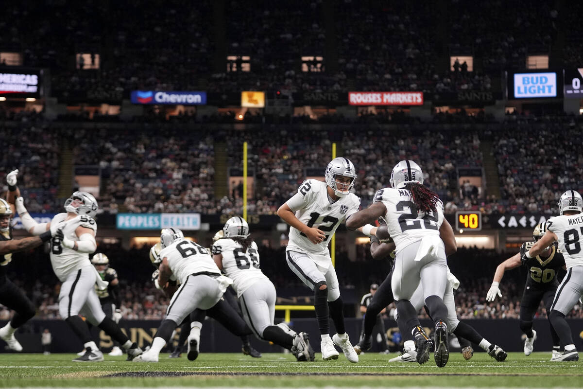 Las Vegas Raiders quarterback Aidan O'Connell (12) hands the ball off to running back Alexander ...