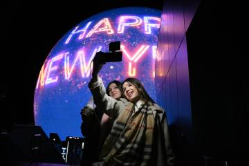 Paulina Mojica, left, and Isabelle Mojica take a selfie as the Sphere displays a Happy New Year ...