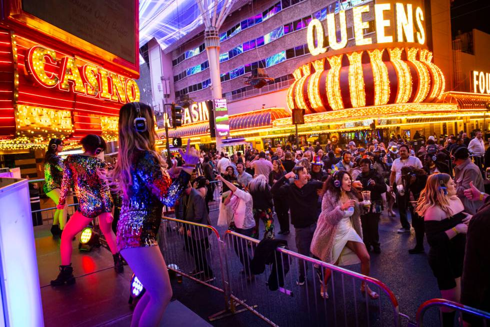 People dance to a silent disco party during the New Year's Eve celebration at the Fremont Stree ...