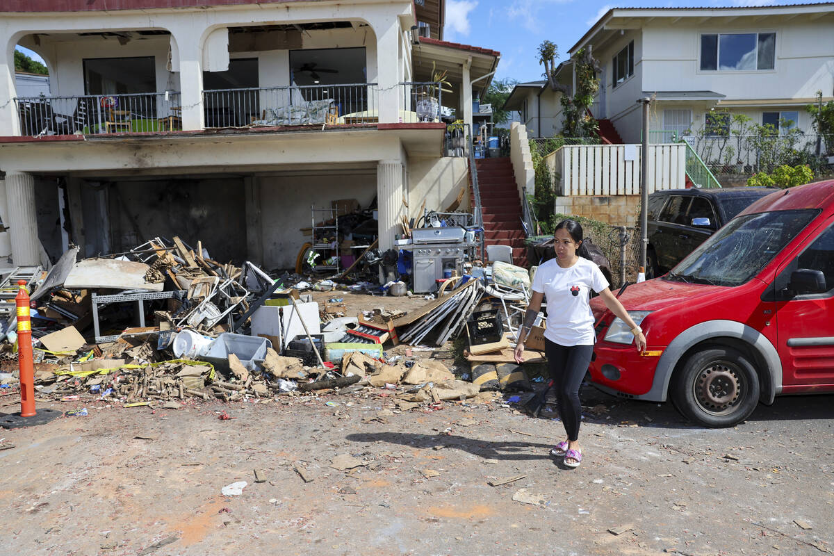 A woman walks in front of the home where a New Year's Eve fireworks explosion killed and injure ...