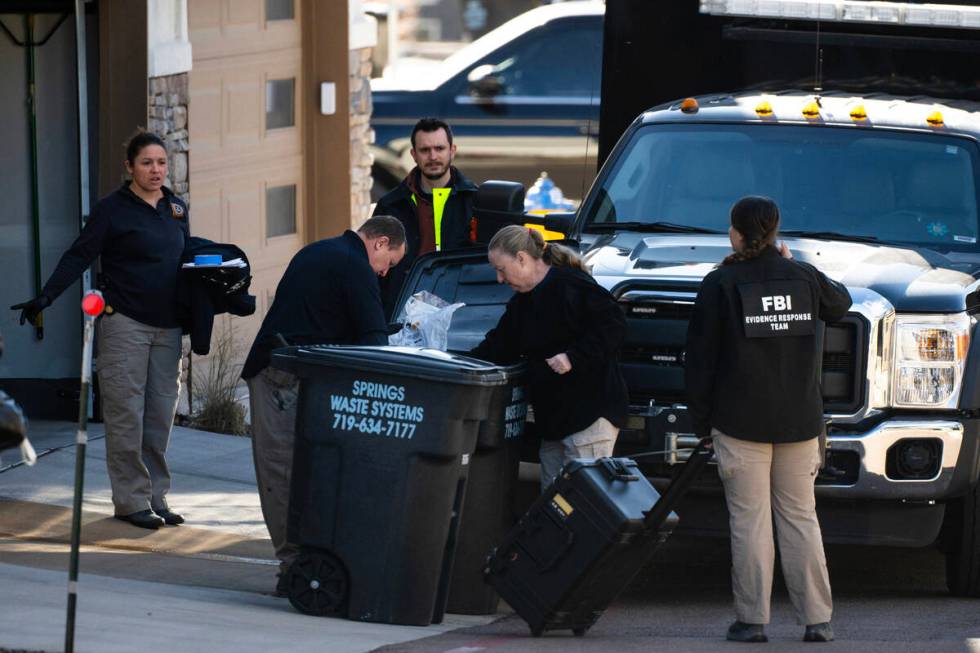 Investigators search the garbage outside of a townhouse in northeastern Colorado Springs, Colo. ...