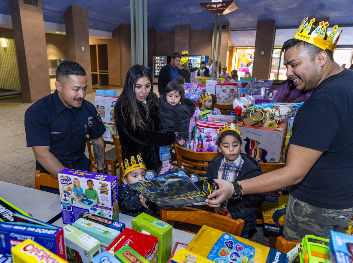 Clark County Firefighter Juan Zelaya, left, joins families as they help find the perfect gift f ...