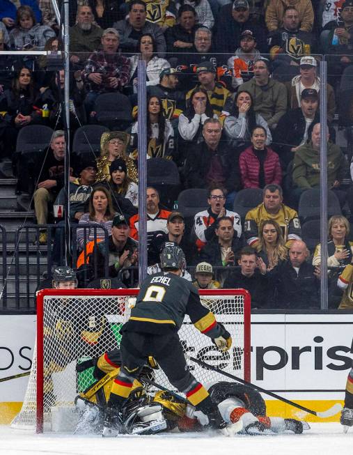 Golden Knights goaltender Adin Hill (33) is taken down in the net by Philadelphia Flyers center ...