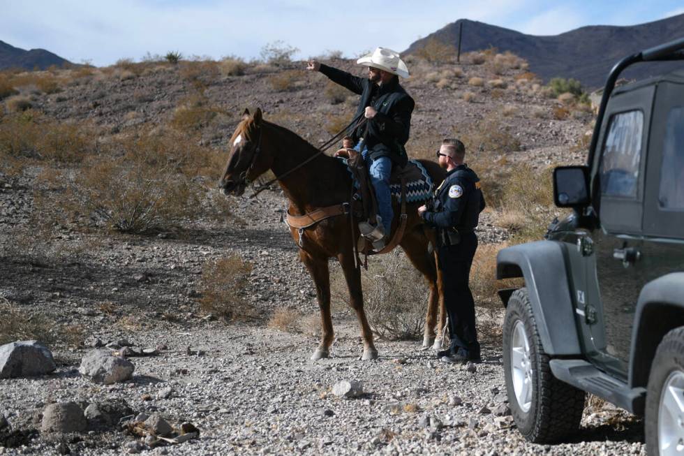 A volunteer on horseback talks with a Henderson police officer during a search for missing teen ...