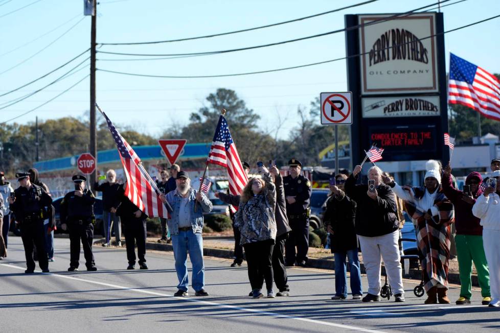 People line the road before the hearse with the casket of former President Jimmy Carter departs ...