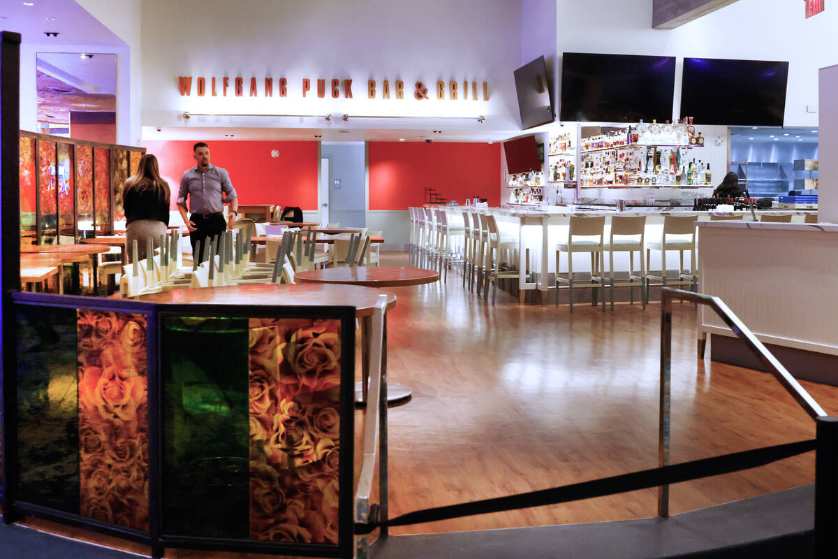 Employees at Wolfgang Puck restaurant set up tables before the reopening of the restaurant at M ...