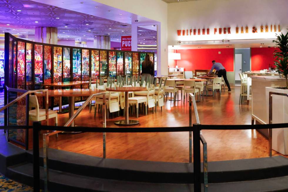 Employees at Wolfgang Puck restaurant set up tables before the reopening of the restaurant at M ...