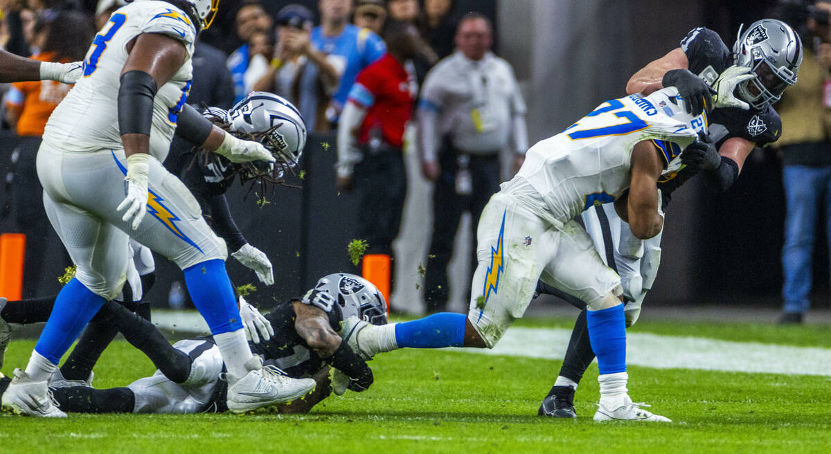 Raiders linebacker Robert Spillane (41) teams up with cornerback Jack Jones (18) to stop Los An ...