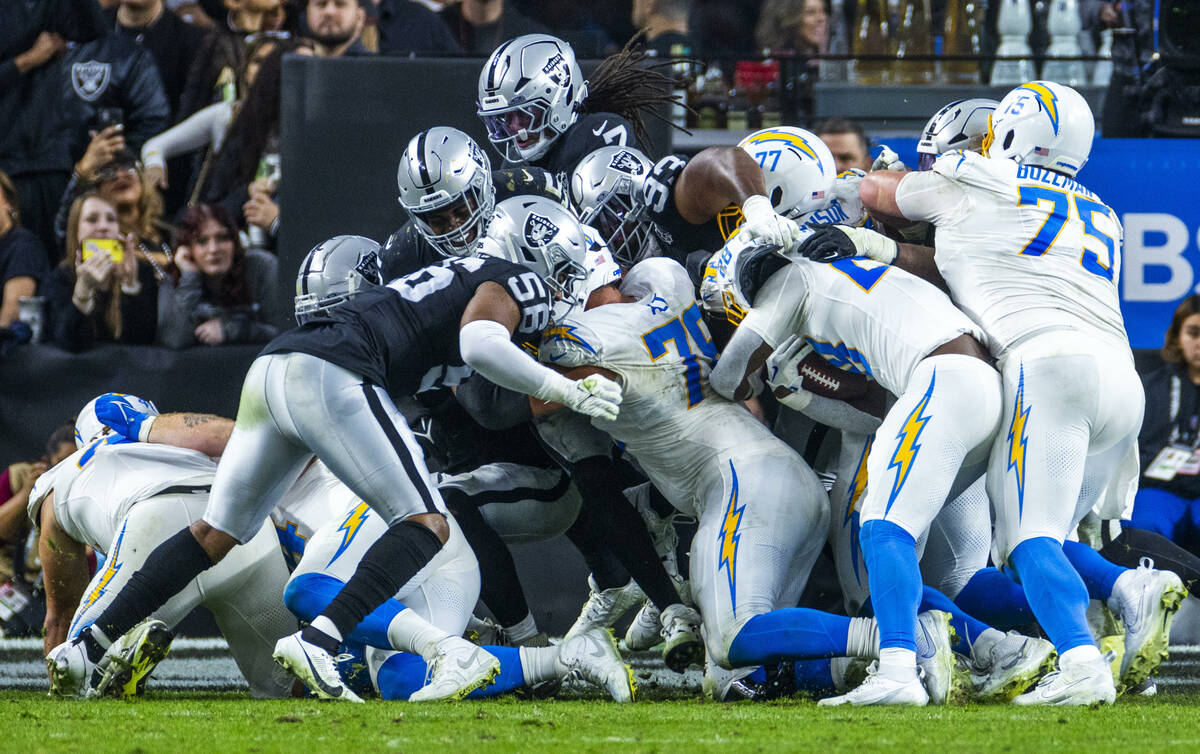 Los Angeles Chargers running back Hassan Haskins (28) is grabbed by Raiders defensive tackle Za ...