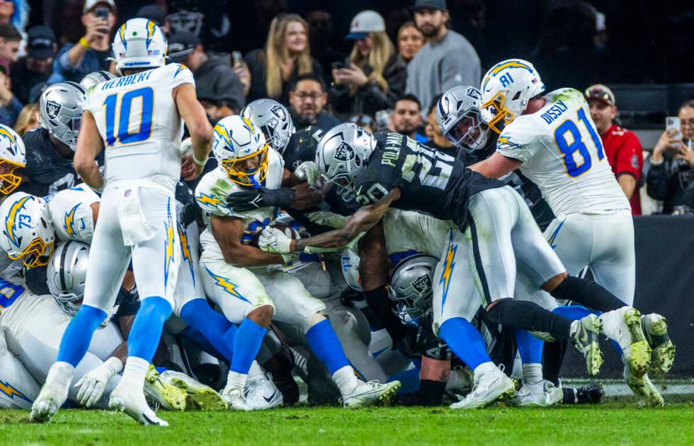 Los Angeles Chargers running back Hassan Haskins (28) is stopped by Raiders safety Isaiah Pola- ...