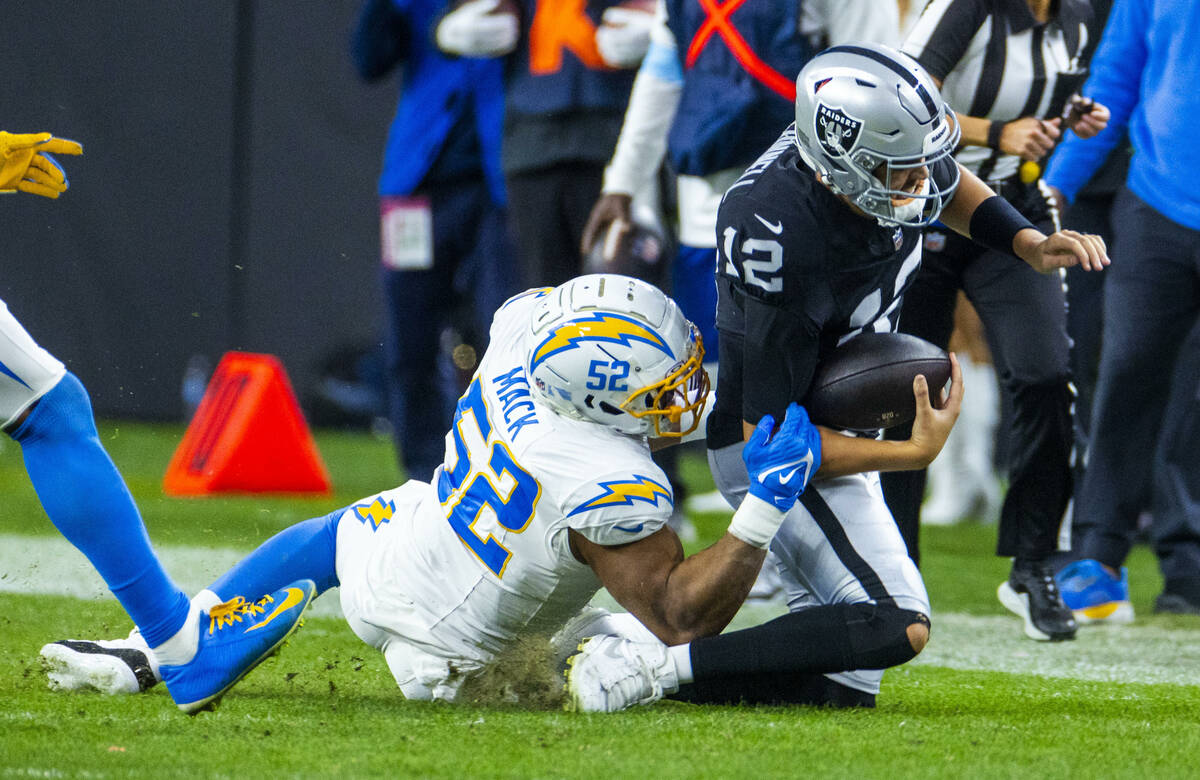 Raiders quarterback Aidan O'Connell (12) is brought down after a run by Los Angeles Chargers li ...