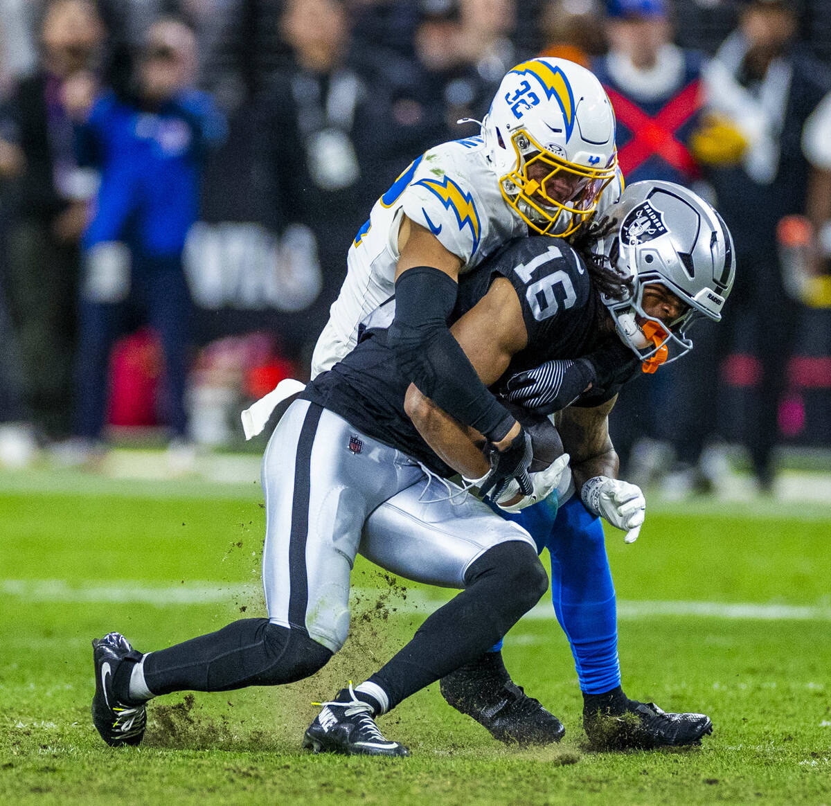 Raiders wide receiver Jakobi Meyers (16) is wrapped up after a catch by Los Angeles Chargers sa ...