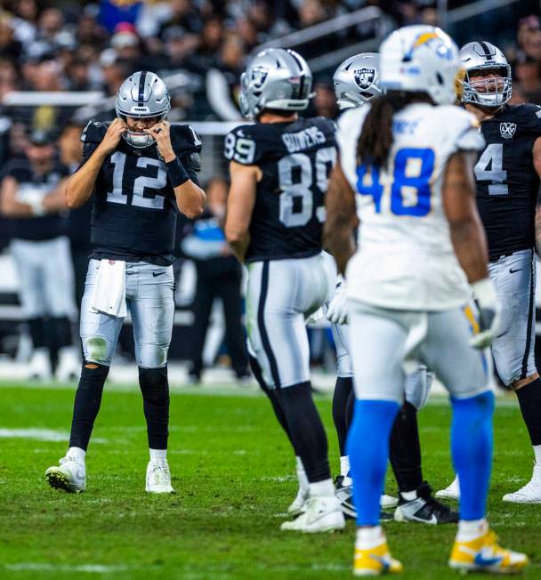 Raiders quarterback Aidan O'Connell (12) clears his head after another hit by the Los Angeles C ...