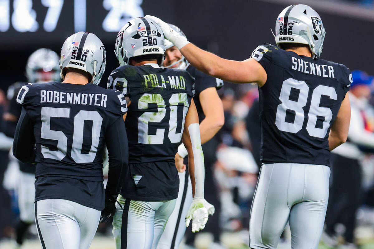 Raiders tight end John Samuel Shenker (86) rubs the head of Raiders safety Isaiah Pola-Mao (20) ...