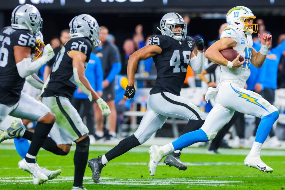 Los Angeles Chargers quarterback Justin Herbert (10) scrambles as Raiders defensive end Charles ...