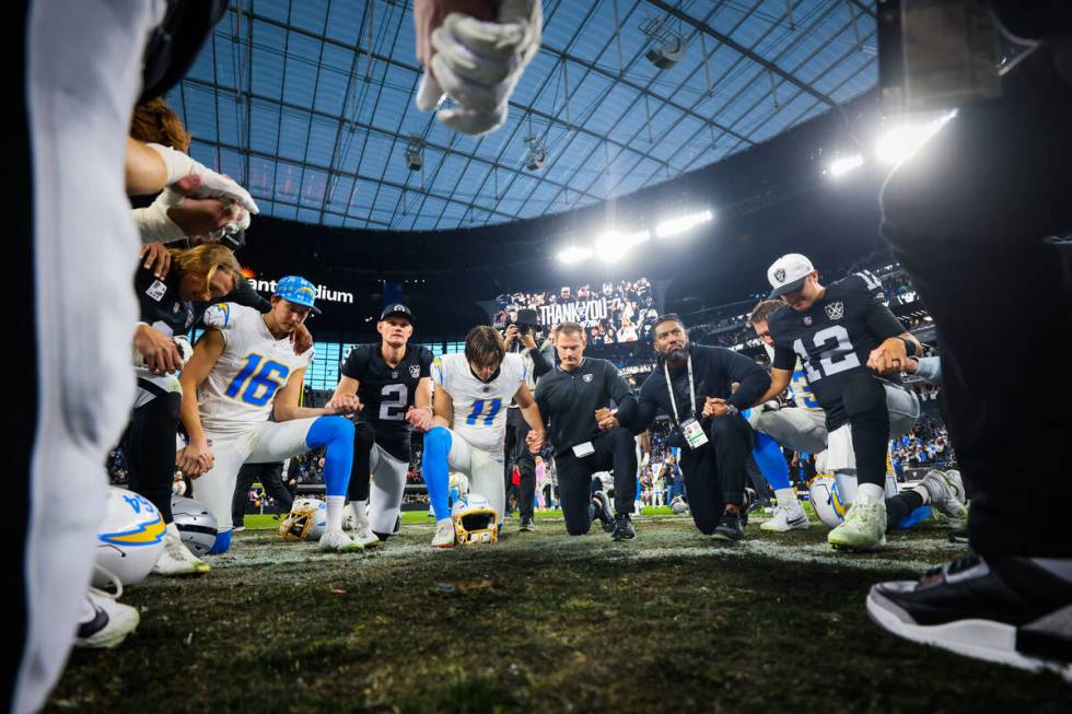 Los Angeles Chargers and Raiders players and staff pray after an NFL football game between the ...