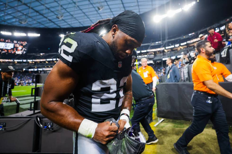 Raiders running back Alexander Mattison (22) autographs a shoe during an NFL football game betw ...